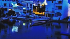 A marina with boats docked, buildings with balconies, and a prominent tower structure. - Beautiful T2 renovated, with bikes, on the water, beach on foot, full center. (Empuriabrava)