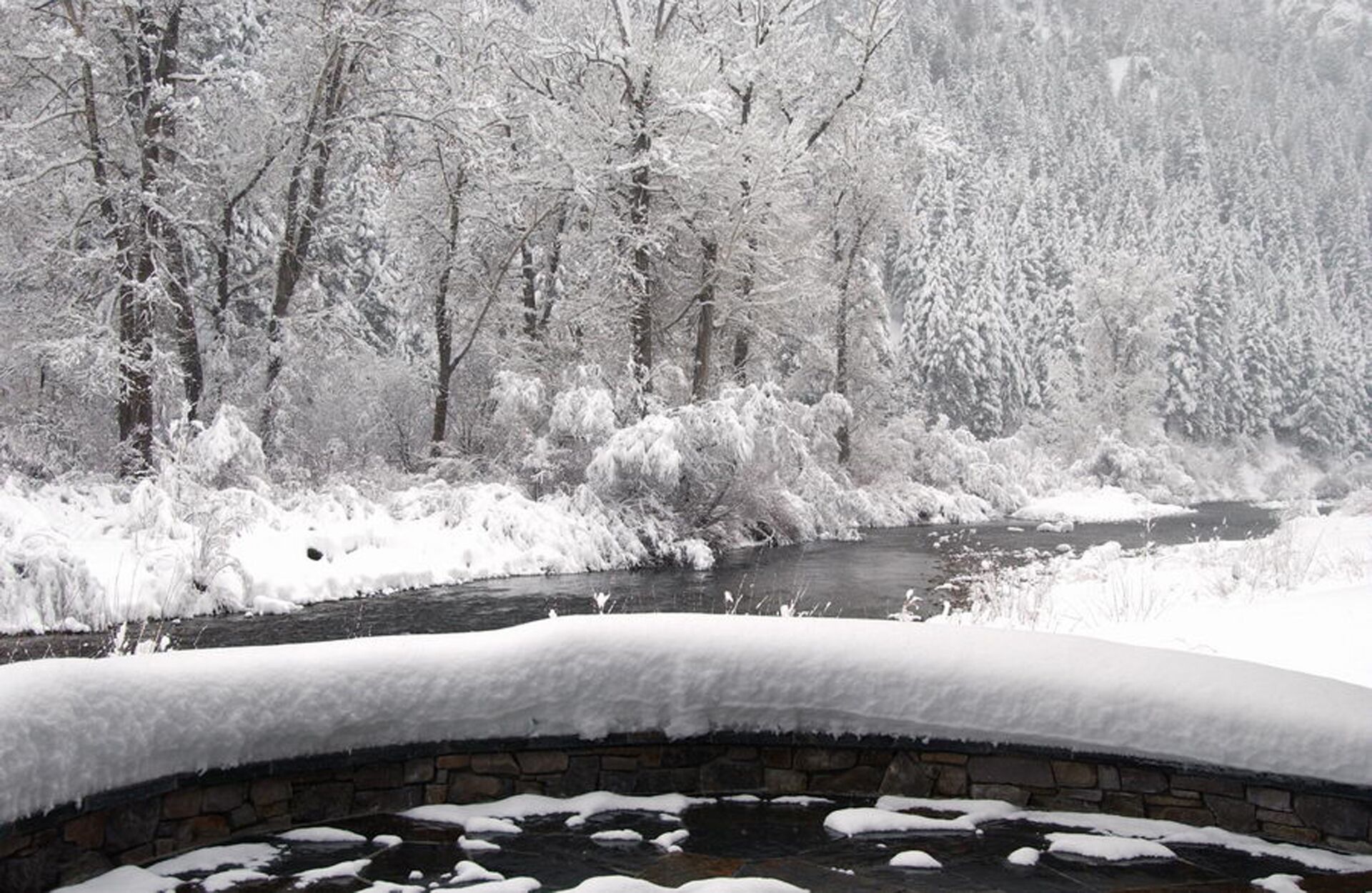 Un puente de piedra sobre un río, con árboles nevados y un paisaje invernal.