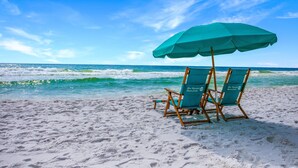 Une plage avec deux chaises de plage et un parasol vert.