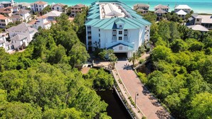 Un grand bâtiment blanc, surmonté d’un toit bleu, entouré d’une végétation luxuriante et offrant une vue sur l’océan.