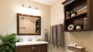 A bathroom with a dark wood vanity, a white toilet, and a shelf with toiletries.