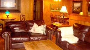 Ein gemütliches Wohnzimmer mit einer braunen Ledersofa, einem Holztisch und einem Essbereich mit Tisch und Stühlen.