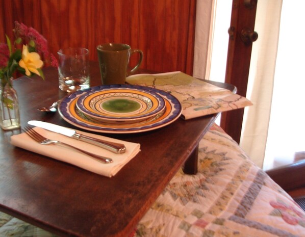 A dining table set with plates, cutlery, and a vase with flowers.