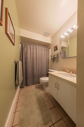 Un baño con inodoro, lavabo, espejo y cortina de ducha.
