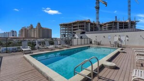 A rooftop pool with a view of a construction site and city buildings in the background. - Walk to Beach & Rooftop Pool by Luxury Resorts (Naples)