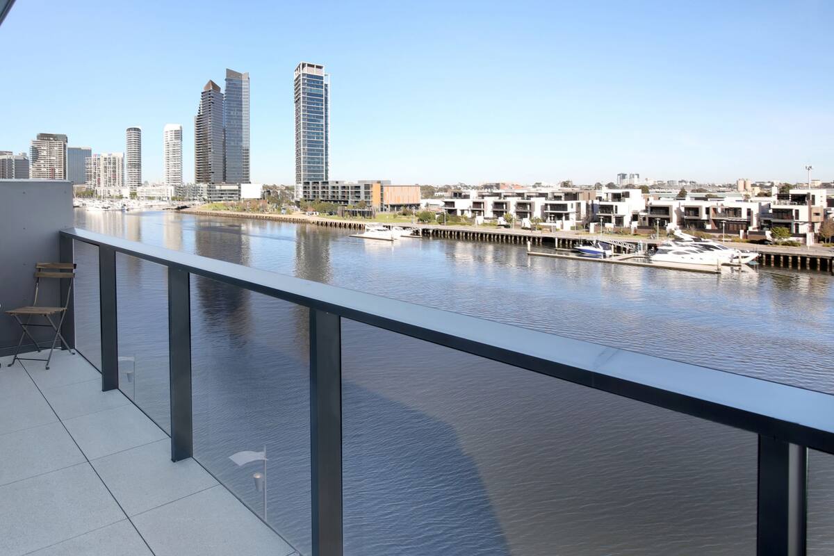A balcony with a view of a marina and city skyline.
