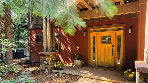 Una casa rústica de fusta amb entrada de pedra, un porxo de fusta i una porta gran de fusta.
