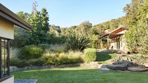 Una casa moderna con un jardín cuidado, un camino de piedra y una pérgola.