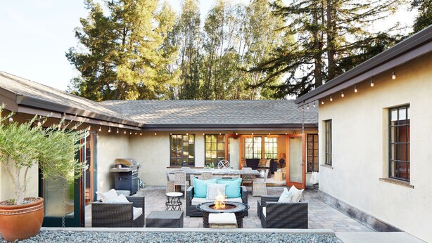 Un patio con mobiliario exterior, una chimenea y vistas de la casa.