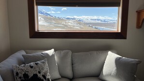 Ein Zimmer mit Fensterblick auf eine verschneite Berglandschaft.