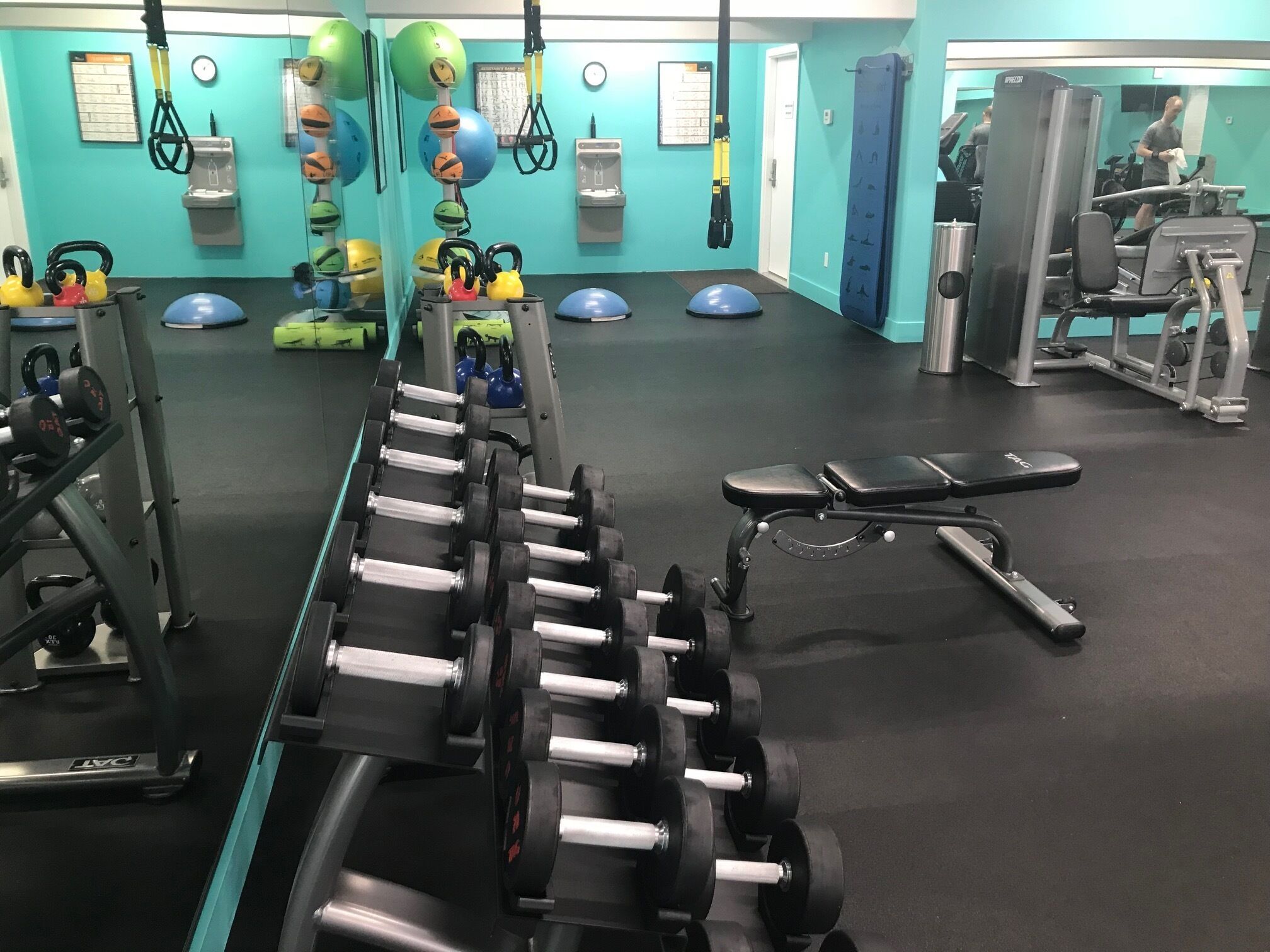 A gym with exercise equipment, including dumbbells, kettlebells, and a bench.