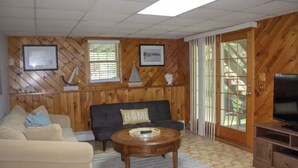 A wooden-paneled living room with a sofa, a coffee table, and a television. - Charming & spacious beach home in Bonnet Shores, Narragansett (Narragansett)
