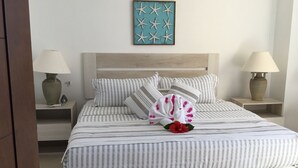 A neatly made bed with striped bedding, a decorative towel, and a wall art piece above it. - Los mejores atardeceres en Ixtapa Zihuatanejo (Ixtapa)