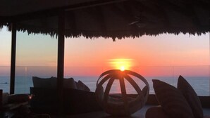 A sunset view from a covered outdoor seating area with a table and chairs. - Los mejores atardeceres en Ixtapa Zihuatanejo (Ixtapa)