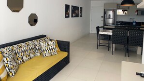 A modern living room with a sofa, a dining area with chairs, a kitchen with a refrigerator, and a ceiling light fixture. - Newly designed apartment - leisure area with infinity pool and incredible views.  (Ingleses Norte)