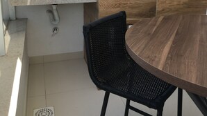 A kitchen with a sink, a wooden wall, a round table, and a black chair. - Newly designed apartment - leisure area with infinity pool and incredible views.  (Ingleses Norte)