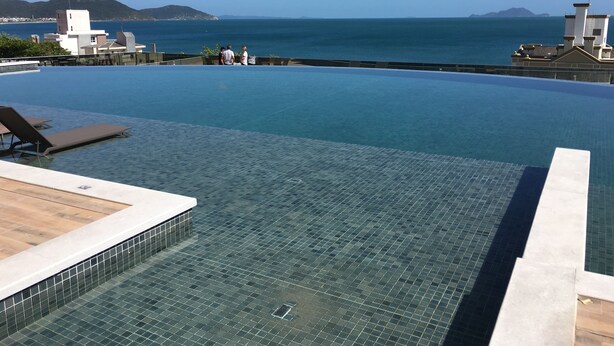 A rooftop infinity pool with clear blue water, a tiled deck, and a view of the sea and distant mountains. - Newly designed apartment - leisure area with infinity pool and incredible views.  (Ingleses Norte)