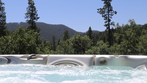 Un jacuzzi con vistas a una ladera boscosa.