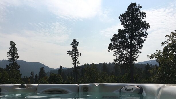 Un jacuzzi con vista despejada a un bosque y montañas al fondo.