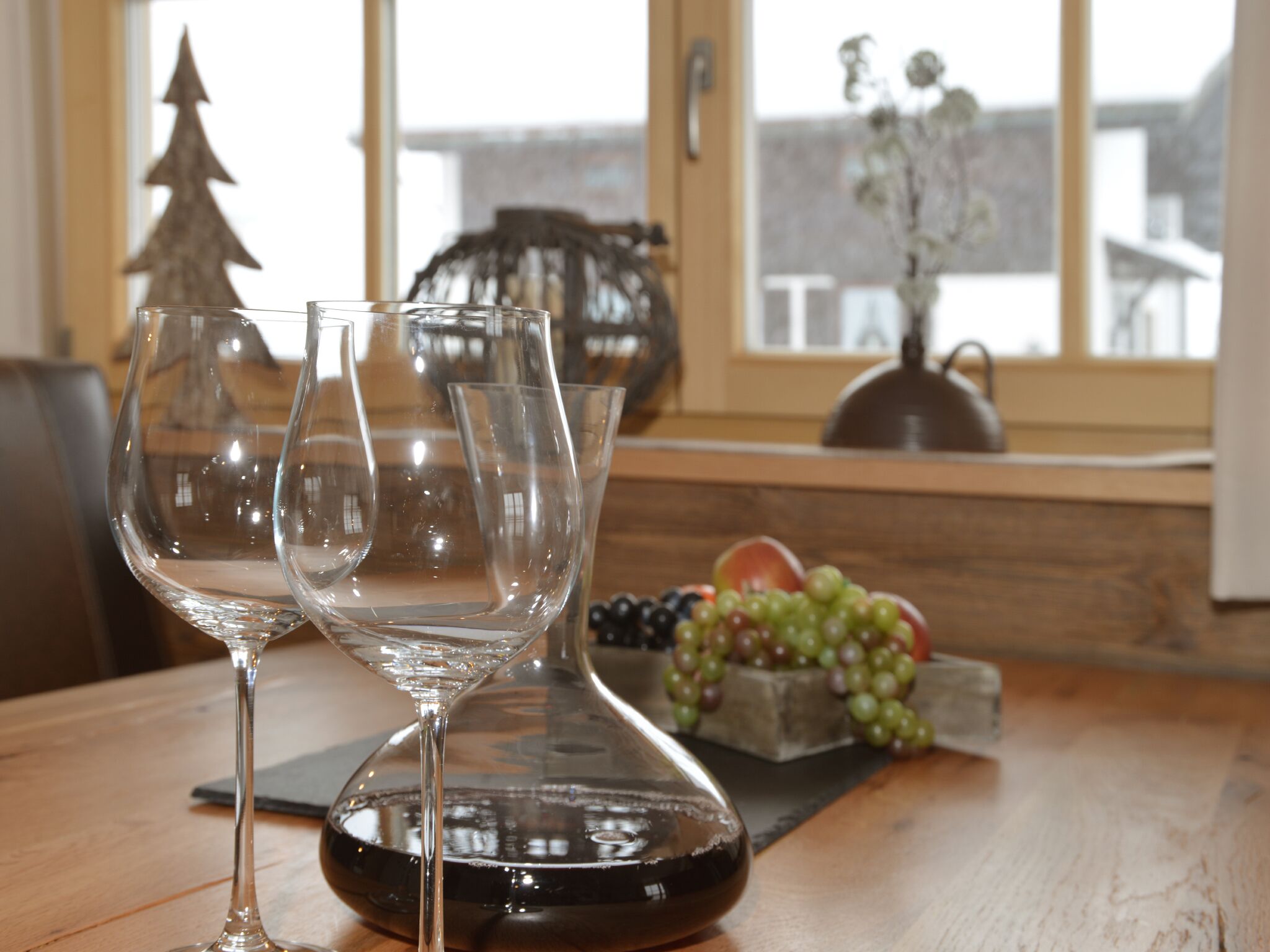 Une table à manger avec trois verres à vin et un saladier de fruits.