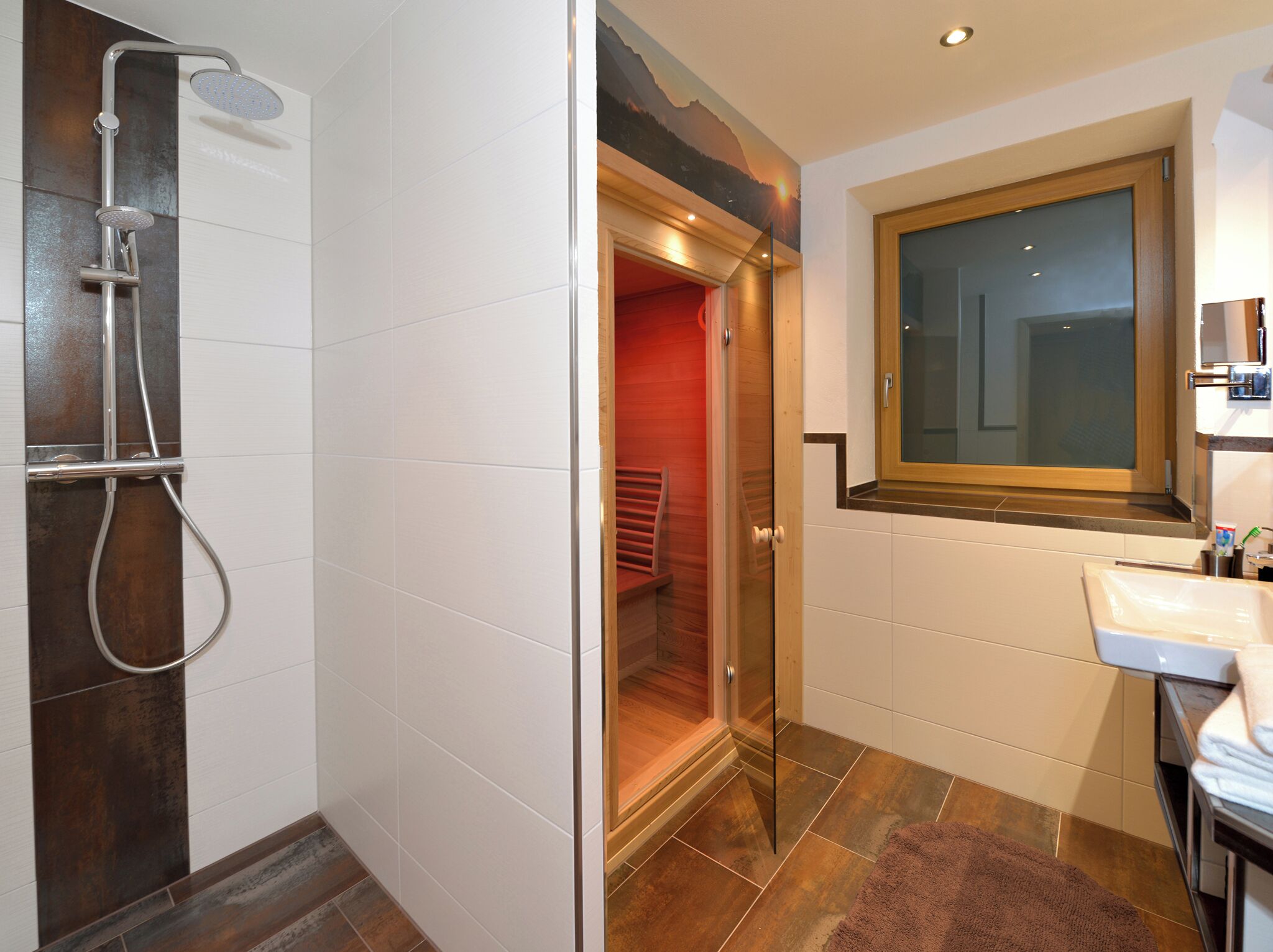 Une salle de bain moderne avec une douche à parois de verre, une porte en bois et un lavabo surmonté d’un miroir.