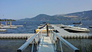 A pier leading to a dock with boats moored at the end. - Bella Cottage @ La Casa Lakeside Resort, 180 Degree View Of Lake Okanagan. (Kelowna)