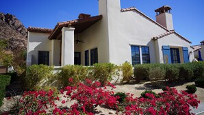 A two-story house with a white exterior, blue shutters, and a red-tiled roof.