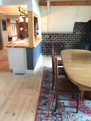 Relax in this open-plan living space with a central kitchen island, dining table, and brick-patterned accent wall.