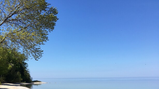 En strand med en träbänk och ett par skor i sanden.