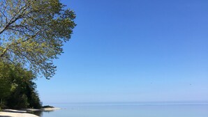 Ein Strand mit einer Holzbank und einem Paar Schuhe im Sand.