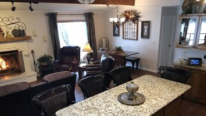 Un salon chaleureux avec une cheminée, un coin repas avec une table et des chaises, et une cuisine dotée de plans de travail en granit.