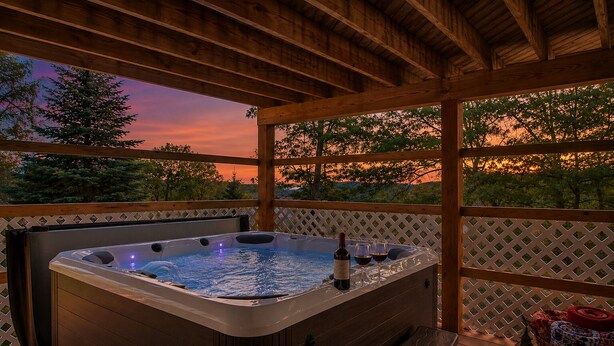Un jacuzzi con una terraza de madera, un banco y un farol.