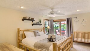 Una cama de madera con cabecera, una mesita de noche, un ventilador de techo y vistas al exterior.