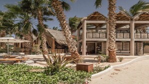 Ein Resort mit Palmen, Außenbestuhlung und einer Struktur mit Reetdach.