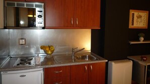 A compact kitchen with wooden cabinets, a stainless steel range, a sink, and a small refrigerator. - Leon apartments with two rooms (León)