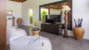 Een moderne woonkamer met een bank, televisie, decoratieve vazen en een grote spiegel.