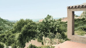 A view of a mountainous landscape with a cactus in the foreground, a stone wall, and a building with a tiled roof. - JULY OFFER Sea View Granite House (Costa Paradiso)