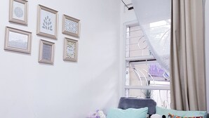 A room with a grey sofa, a clock on the wall, and framed pictures.