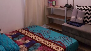 A bedroom with a bed, a TV, a desk, and a sofa.
