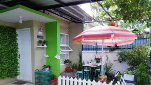 A patio with a white picket fence, a table with chairs, and potted plants.