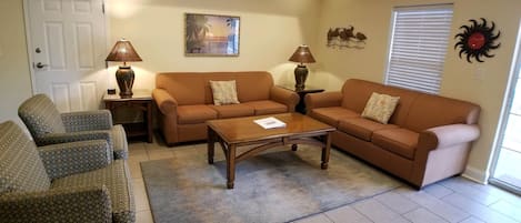 A living room with a sofa set, two armchairs, a coffee table, and a lamp.