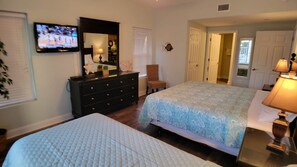 Un dormitorio con cama, cómoda, televisor y una silla.
