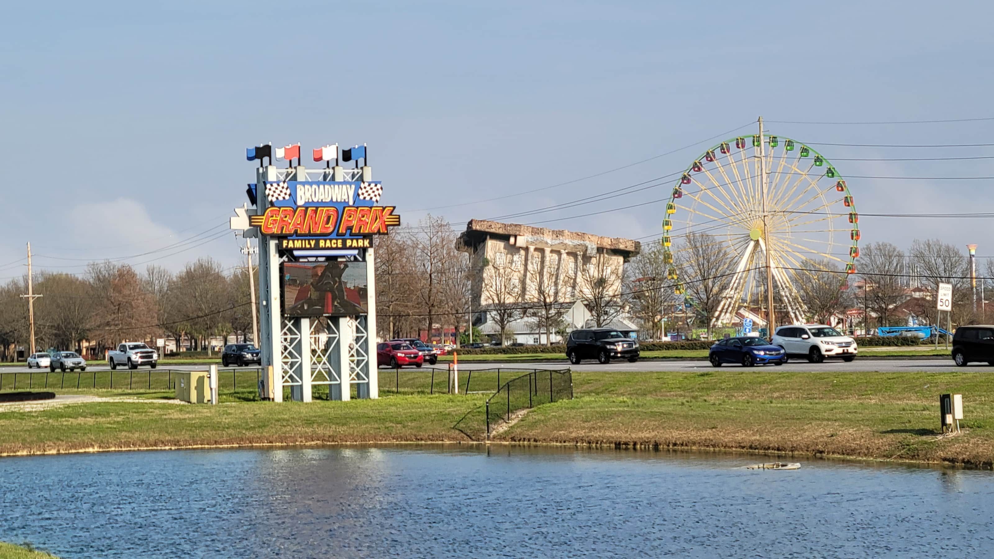 A sign for a family race park with a Ferris wheel in the background.