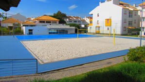 A beach volleyball court with a net, surrounded by a sandy area and a blue pool. -   Modern 1 bedroom apartment on the sea front of Cabanas De Tavira   (Cabanas de Tavira)