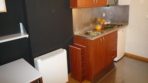 Une cuisine compacte avec des meubles en bois, un évier en acier inoxydable et un four à micro-ondes encastré.