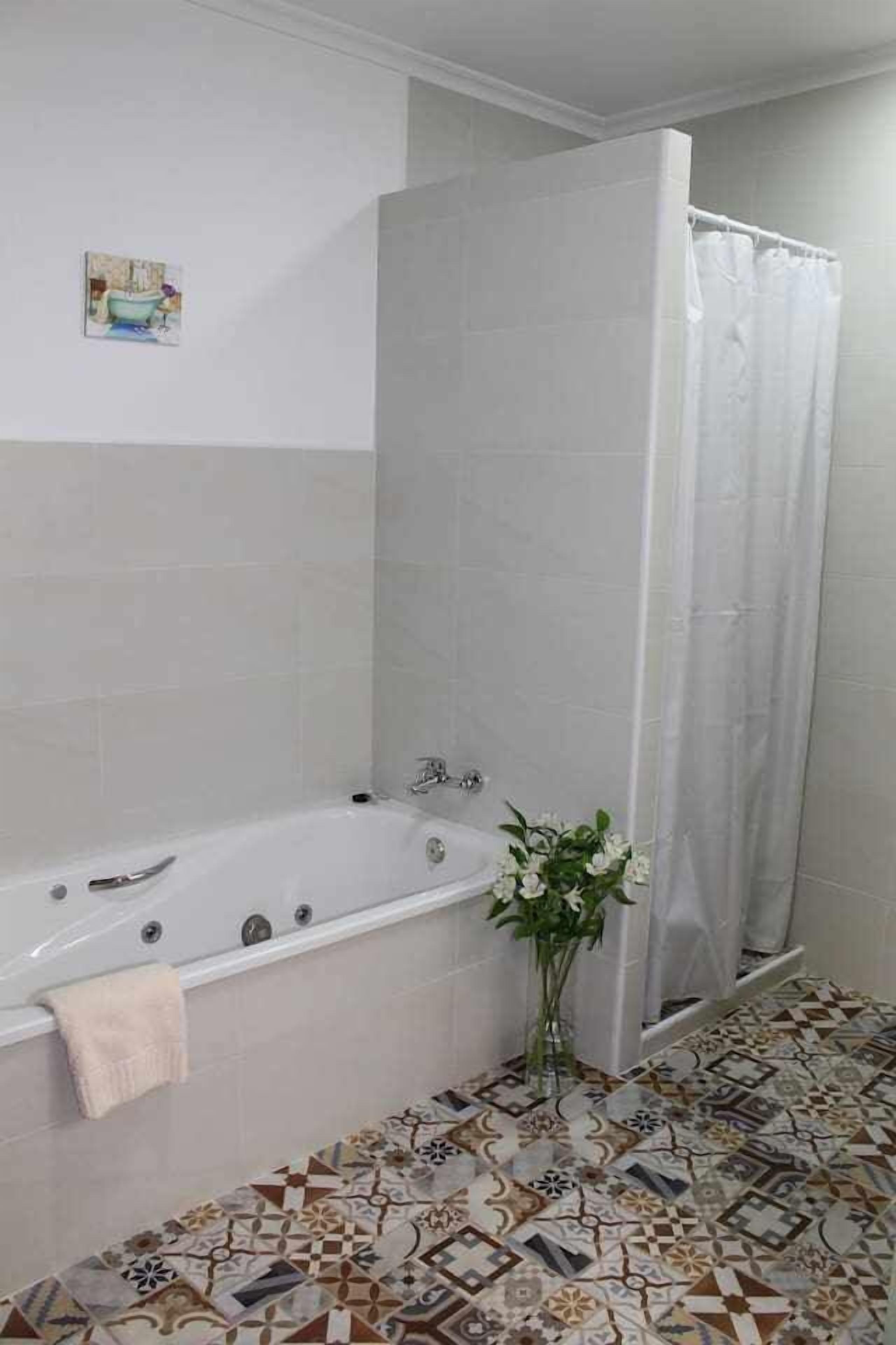 A bathroom with a bathtub, a shower curtain, and a tiled floor.