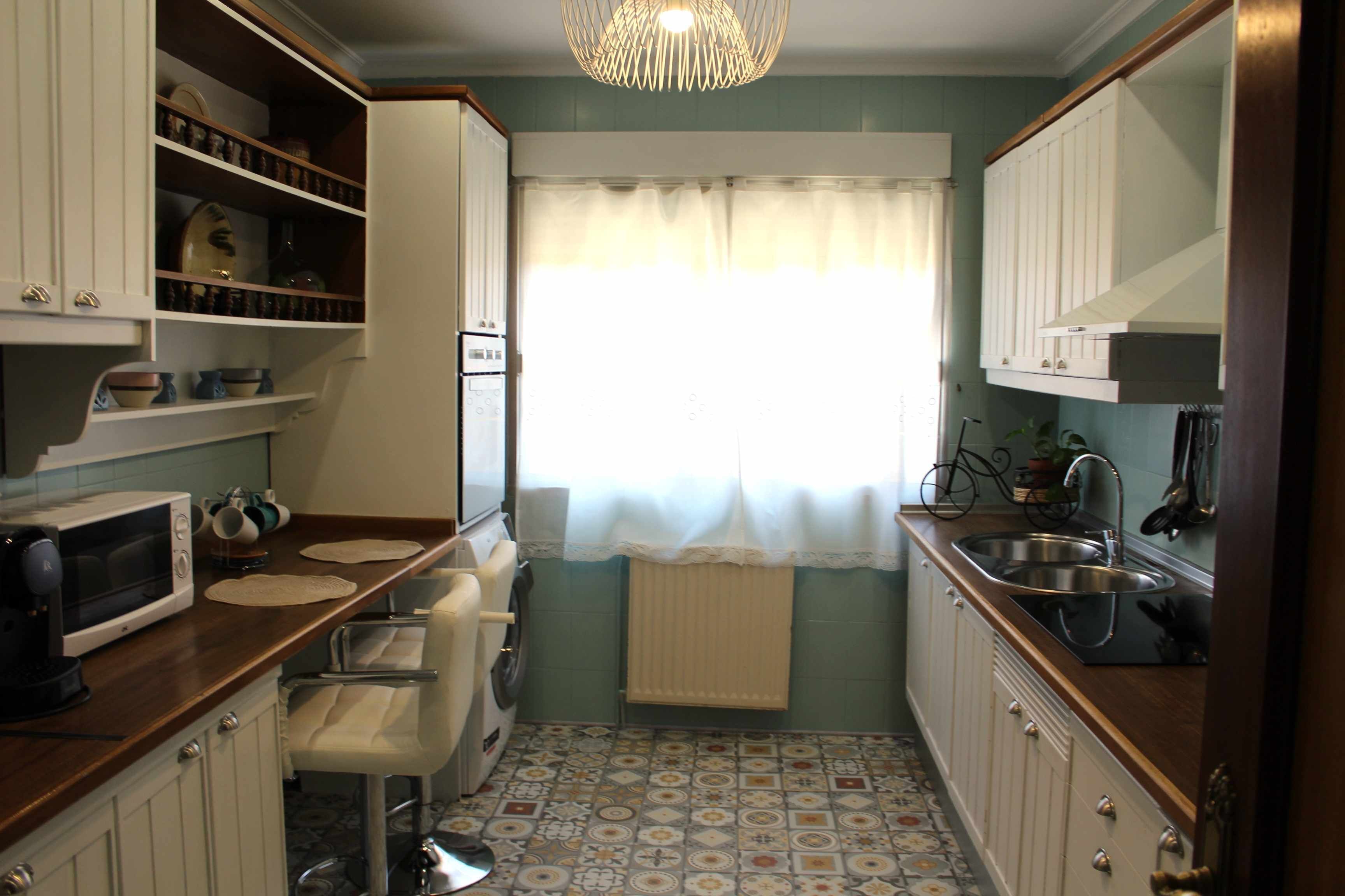 Een kleine keuken met een wasmachine, een magnetron en een spoelbak.