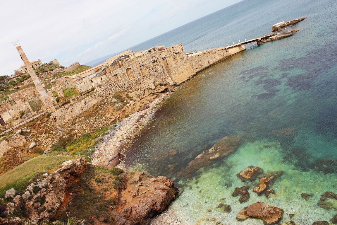 A coastal historical site with ruins and clear waters.