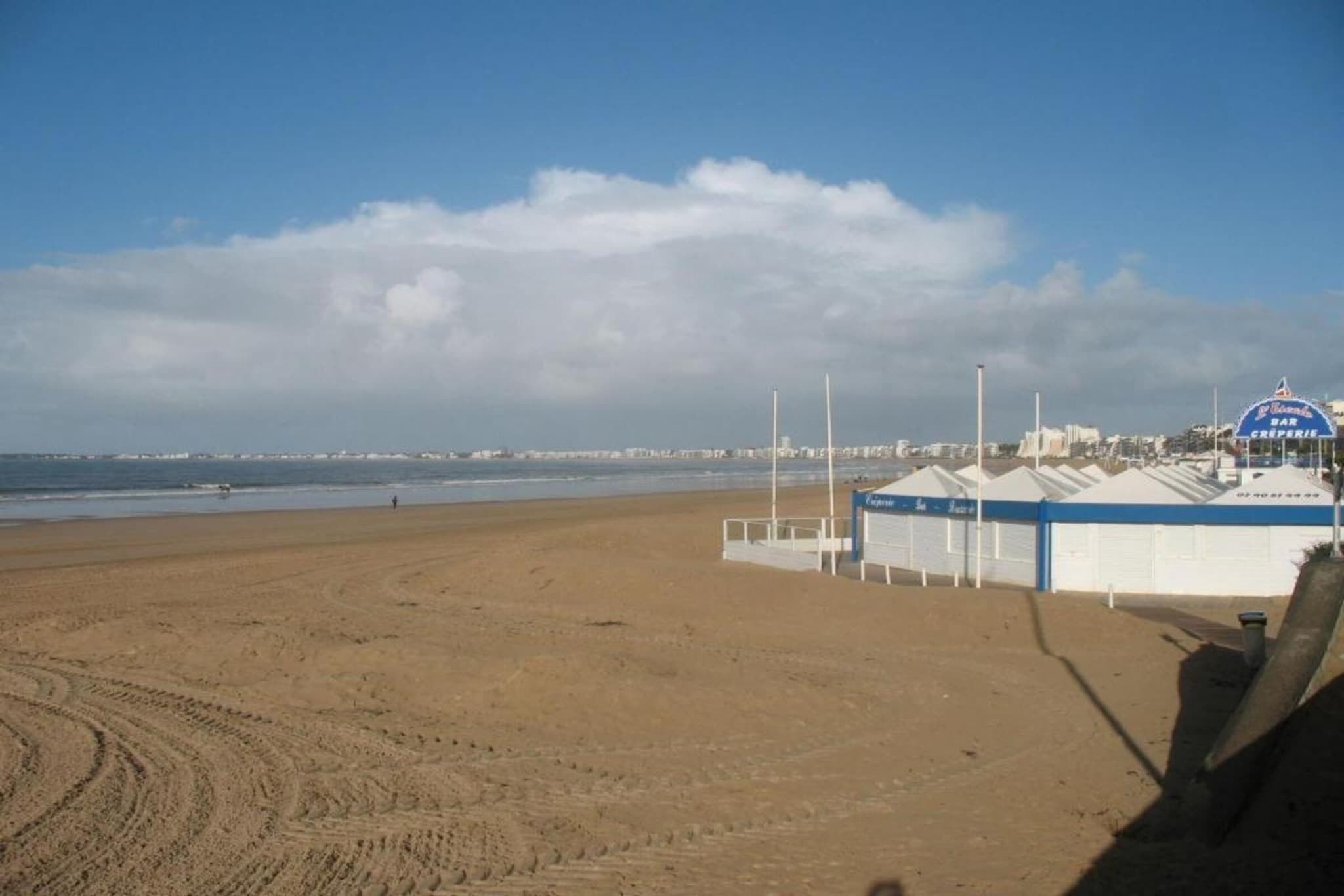 A beach with a row of beach huts and a clear sky.