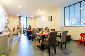 A dining area with tables and chairs, a counter with a cash register, and a fire extinguisher on the wall. - Apartment in La Baule with Sea View (PORNICHET)